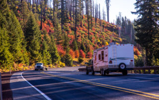 Fall colors with RV travel trailer being towed on a road